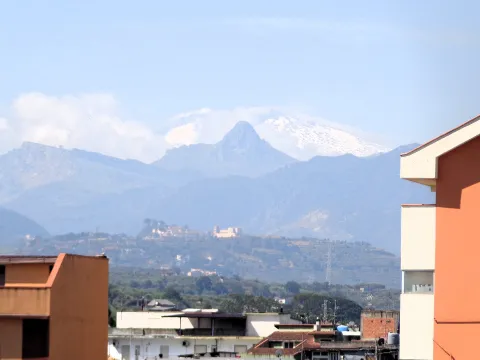 Panoramic view of snow-covered Mount Etna and the peak of Rocca di Novara in Sicily.