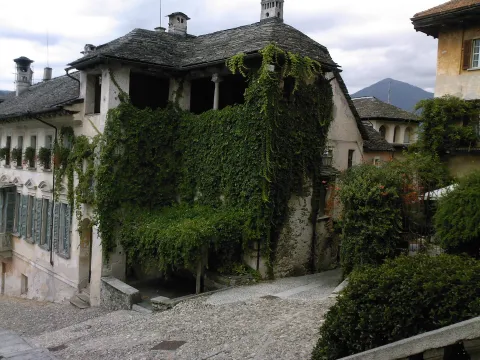 Cobblestone lane with vine-covered historic stone buildings in Orta San Giulio