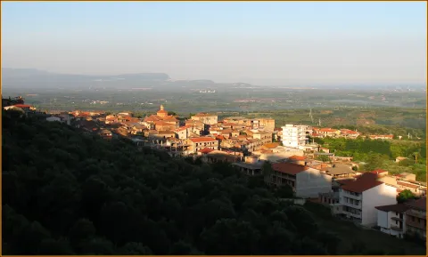 Panoramic view of a hillside town with red roofs overlooking a broad plain
