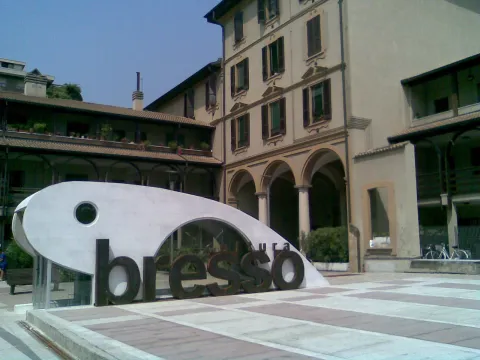 Interno di una chiesa moderna a Bresso con banchi e altare coperto da un drappo rosso