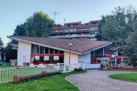 Struttura scolastica con i caratteristici edifici residenziali di Milano 2 sullo sfondo a Segrate