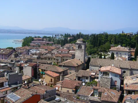 Elevated view over the rooftops of Sirmione with a church bell tower and Lake Garda in the background