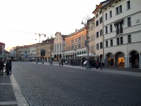 View of Piazza dei Martiri in Belluno featuring porticoed buildings and cobblestone paving.