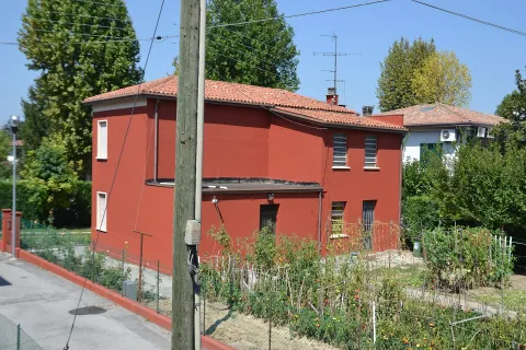 Red residential building with a vegetable garden in Vigonza, Italy