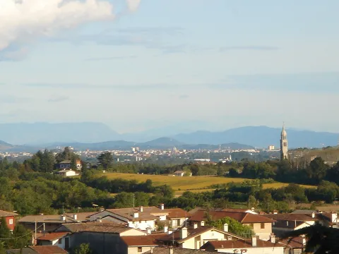 Panoramic view of the Friulian countryside and Udine skyline with mountains in the distance.