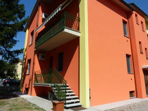 Bright orange residential building in Fidenza with balcony and staircase