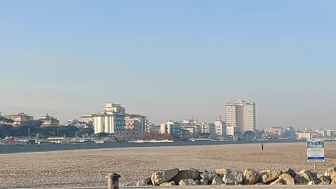Sandy beach and skyline of Cervia with coastal buildings in the background
