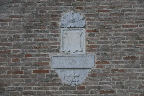 Carved stone coat of arms mounted on a brick wall in Falconara Marittima, Marche
