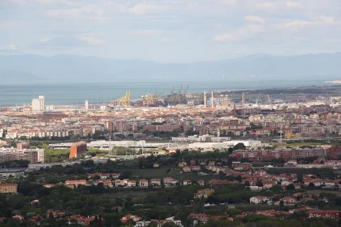 Panoramic view of Livorno from above, showing the city, industrial port cranes, and the sea.