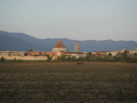 Skyline view of Pisa showing the Baptistery and Leaning Tower with mountains behind