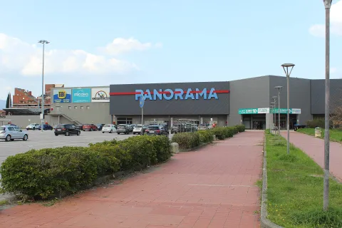 Exterior of the Panorama shopping center in Pontedera with parking lot and pedestrian path