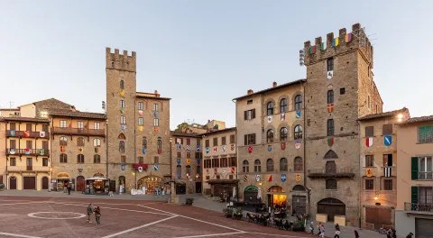 Vista di Piazza Grande ad Arezzo con palazzi medievali e stemmi araldici.