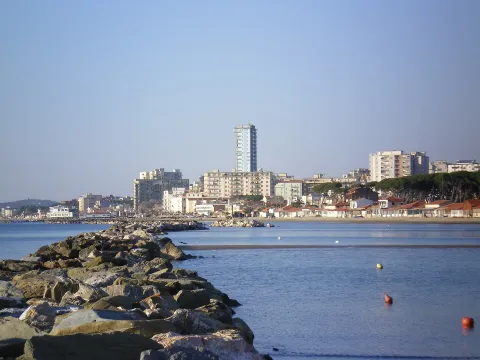 Rocky breakwater in the foreground leading to the beach and skyline of Follonica