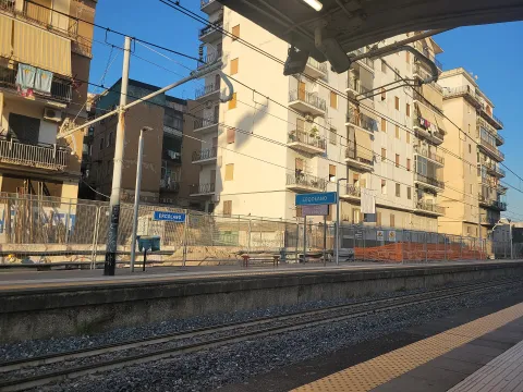 Vista della banchina della stazione ferroviaria a Ercolano con edifici sullo sfondo.
