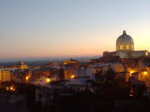 Veduta panoramica al tramonto di Massafra con la cupola illuminata del Duomo