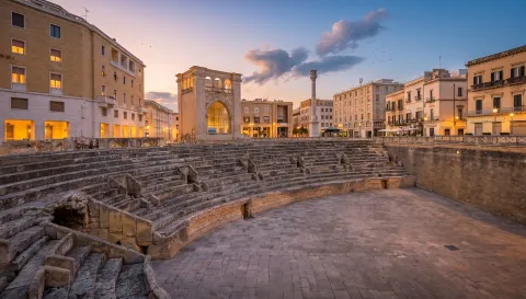 Panoramic night view of Piazza Castromediano in Lecce with outdoor cafe seating.