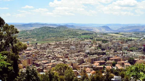 Vista di una strada di Caltanissetta con un edificio storico e alberi