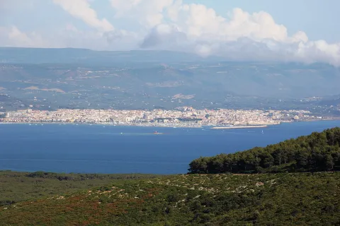 Vista panoramica della città di Alghero e del suo golfo con le colline sullo sfondo.