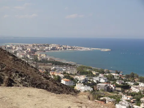 Panoramic view of the town of Crotone, its coastline, and harbor from a hilltop.