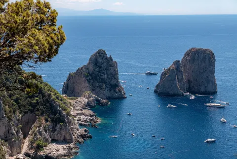 The Faraglioni rock formations in Capri surrounded by blue sea.