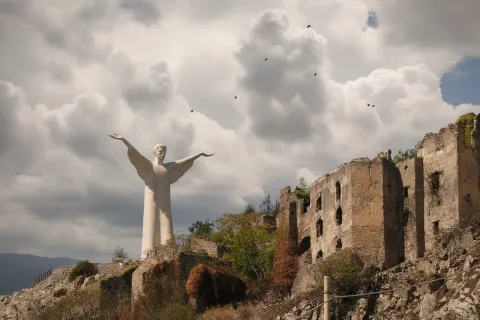 Il Cristo Redentore di Maratea su Monte San Biagio accanto a vecchie rovine in pietra.