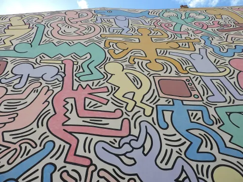 Detail of Keith Haring's colourful Tuttomondo mural on a wall in Pisa, Italy.