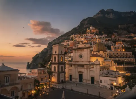 Facade and bell tower of the Church of Santa Maria Assunta in Positano with colorful cliffside houses.