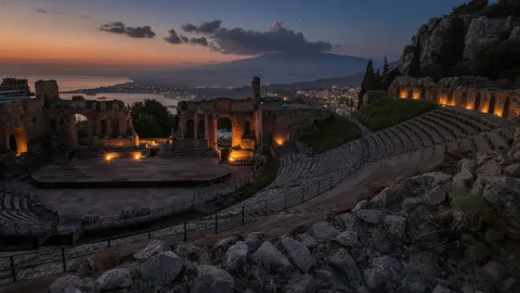 Ancient Theatre of Taormina at sunset with views of the coastline and sea.