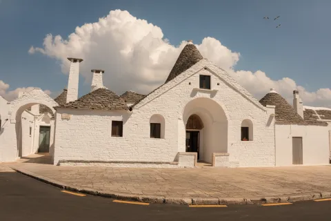 Trullo Sovrano in Alberobello with a white whitewashed facade and traditional conical stone roofs.