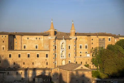 Facade of the Ducal Palace in Urbino featuring its iconic twin towers in warm light
