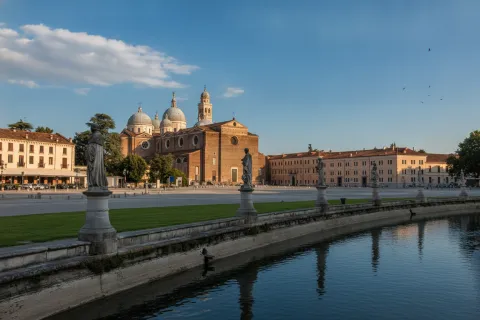 Prato della Valle in Padua with statues along the canal and Santa Giustina Abbey in the background.