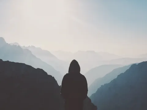 Silhouette of a person looking out at misty mountain peaks near Tre Cime di Lavaredo.