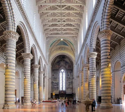 Interno della navata del Duomo di Orvieto con colonne a strisce e affreschi sul fondo