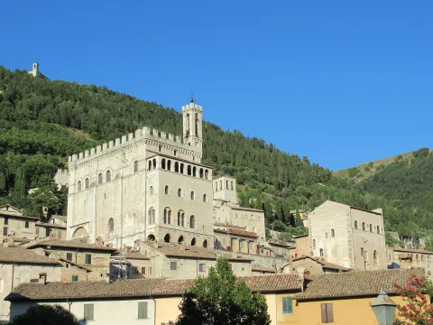 The Palazzo dei Consoli in Gubbio featuring its tower against the green Monte Ingino.