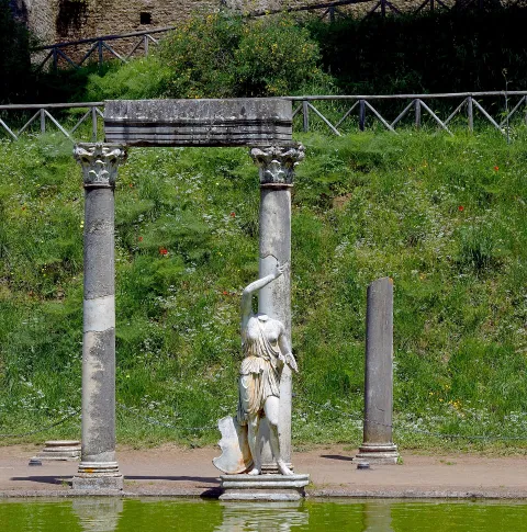 Headless classical statue and ancient Roman columns at the Canopus of Villa Adriana in Tivoli.