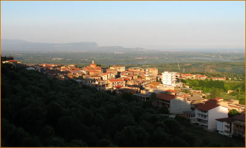 Panoramic view of a hillside town with red roofs overlooking a broad plain