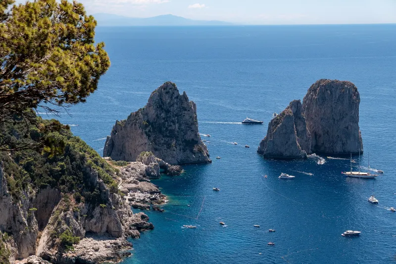 The Faraglioni rock formations in Capri surrounded by blue sea.