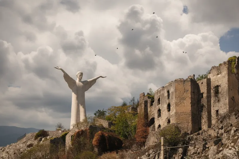 Il Cristo Redentore di Maratea su Monte San Biagio accanto a vecchie rovine in pietra.