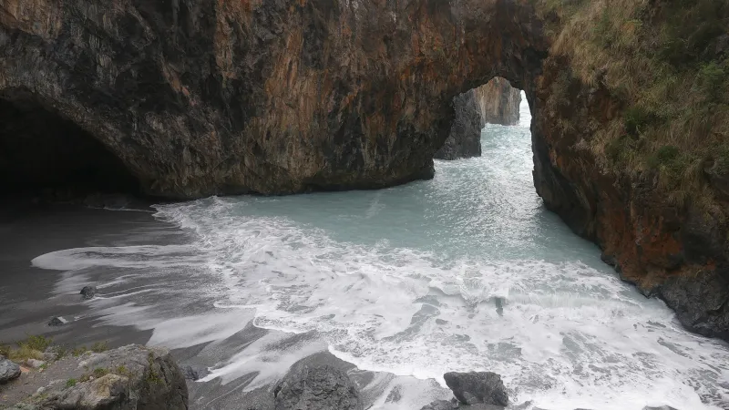 The Arcomagno natural rock arch and cove with turquoise waves in San Nicola Arcella, Italy.