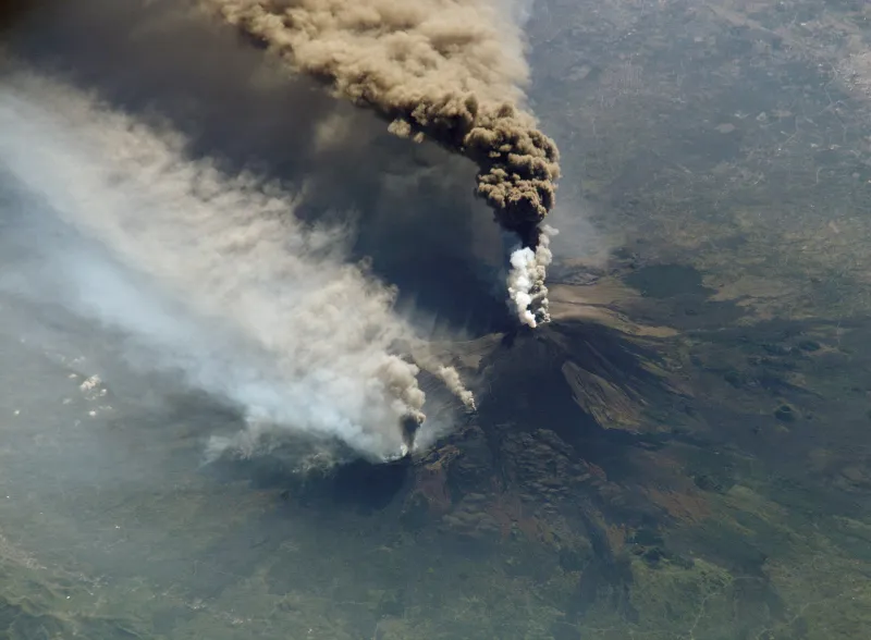 Vista dall'alto dell'Etna (versante sud) in eruzione con una colonna di ceneri.