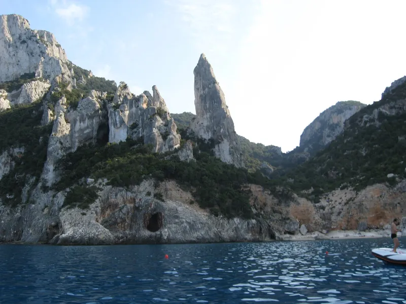 L'iconica Aguglia di Cala Goloritzé a Baunei vista dal mare turchese della Sardegna.