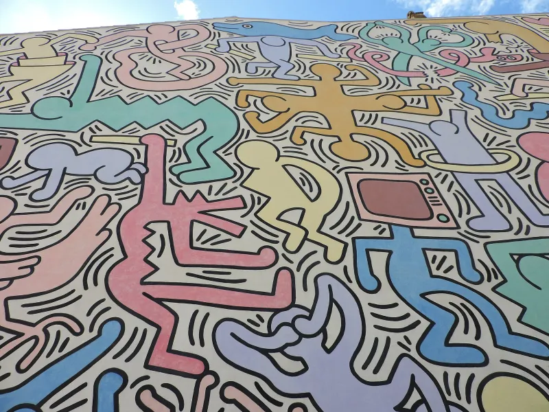 Dettaglio del murale Tuttomondo di Keith Haring a Pisa con figure colorate in stile pop art.