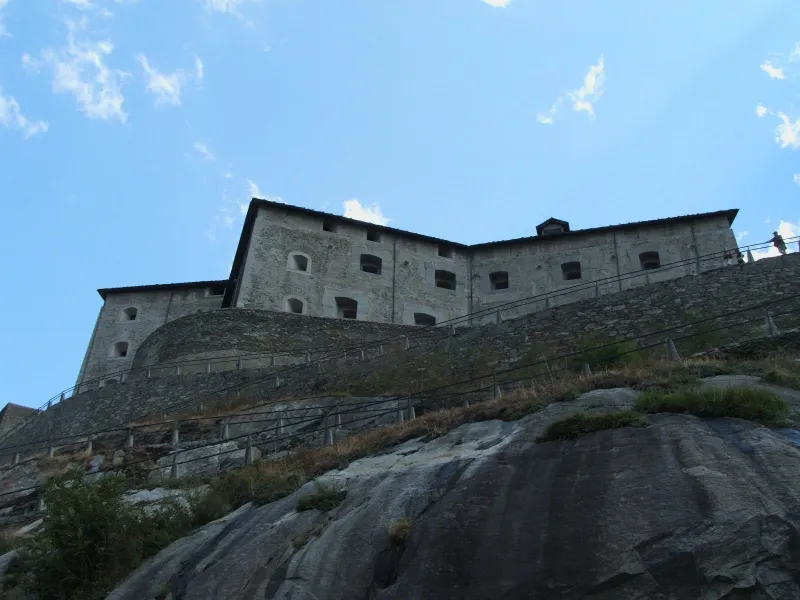 vista dal basso delle imponenti mura in pietra del Forte di Bard abbarbicato sulla roccia