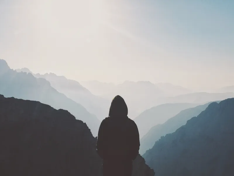Silhouette of a person looking out at misty mountain peaks near Tre Cime di Lavaredo.